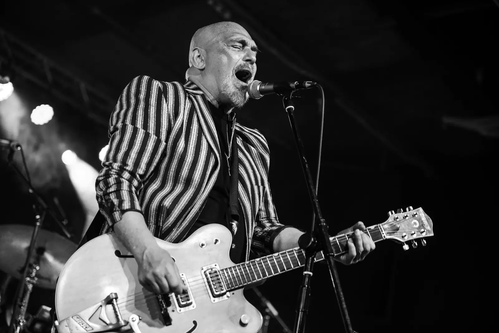 Joe Camilleri in a striped suit playing a white Gretsch guitar, black and white