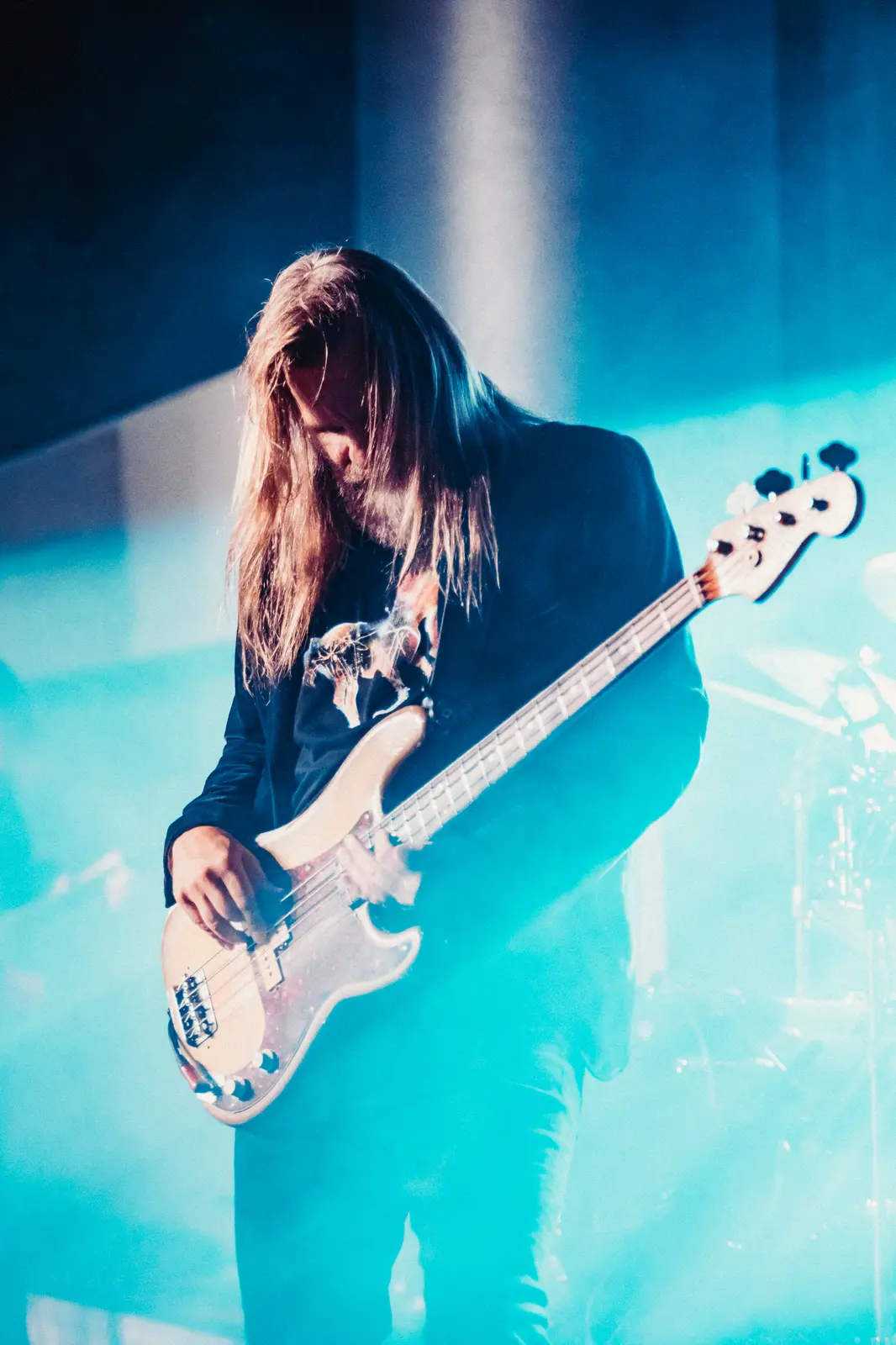 Bassist in teal light, hair mid-swing