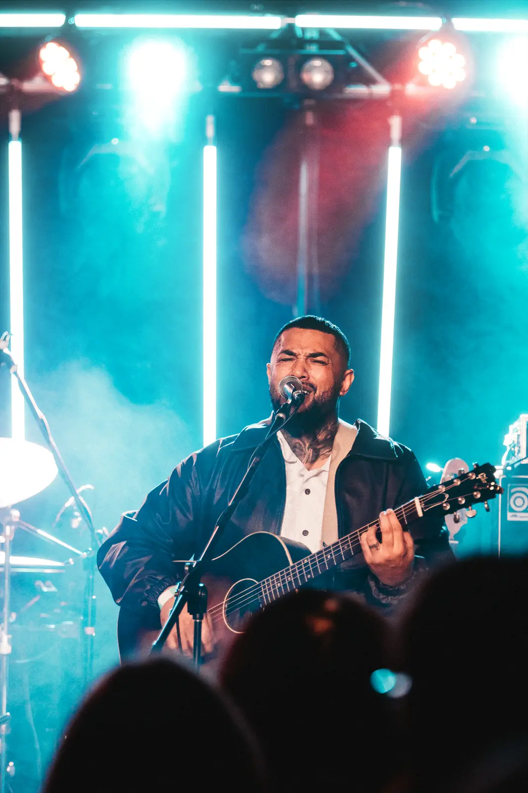 Performer in stage haze with crowd silhouettes below