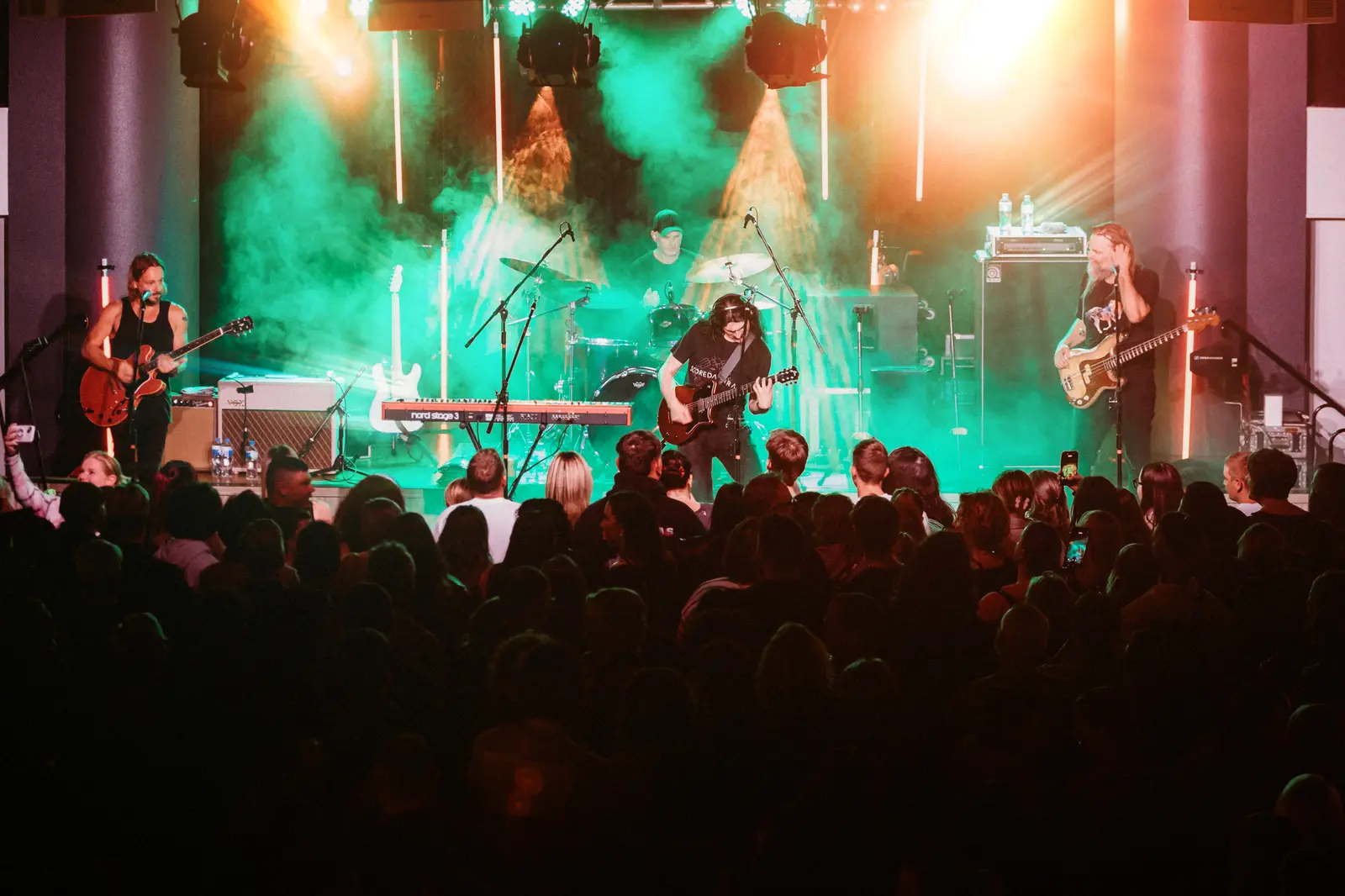 Two guitarists on a green-washed stage above the crowd