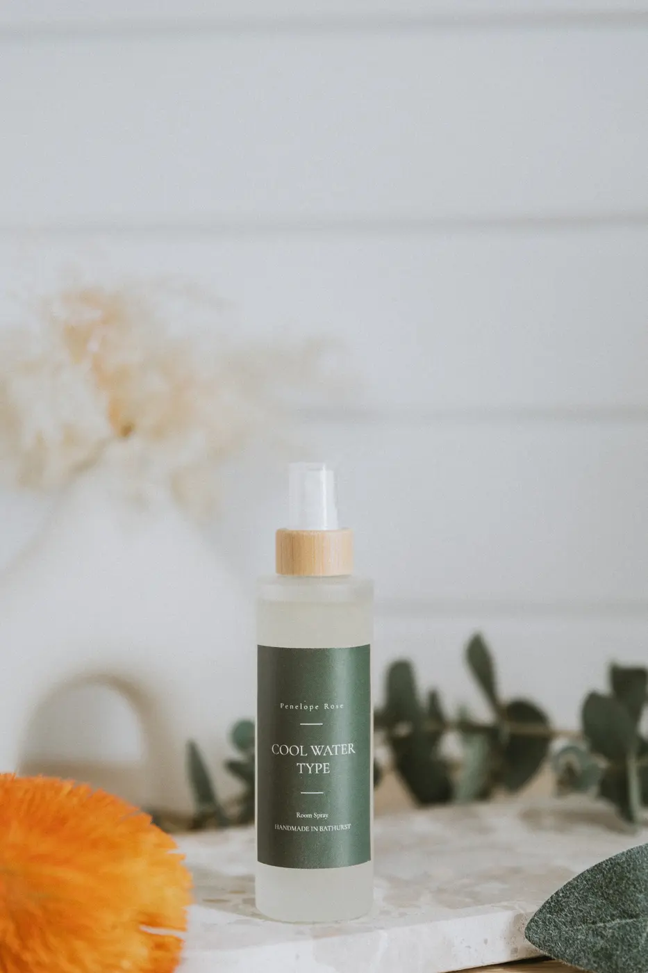 Frosted room spray bottle with bamboo top styled with eucalyptus on stone